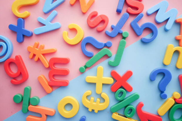 Plastic letters and symbols scattered across a pink and blue surface