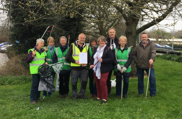 Minister Coffey (centre) with a group of people holding litter-pickers and bin bags on grass