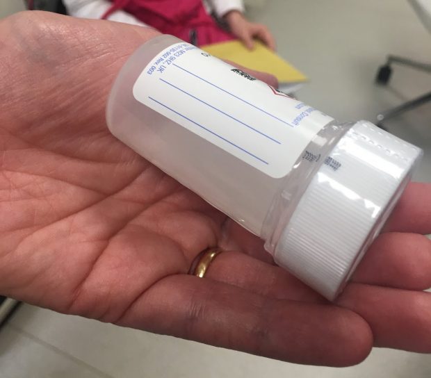 A hand holding a sample tube