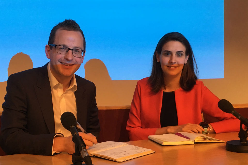 Man and woman seated at desk with microphones