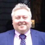 Head and shoulders of Rob Holmes in front of a black door (No. 10)