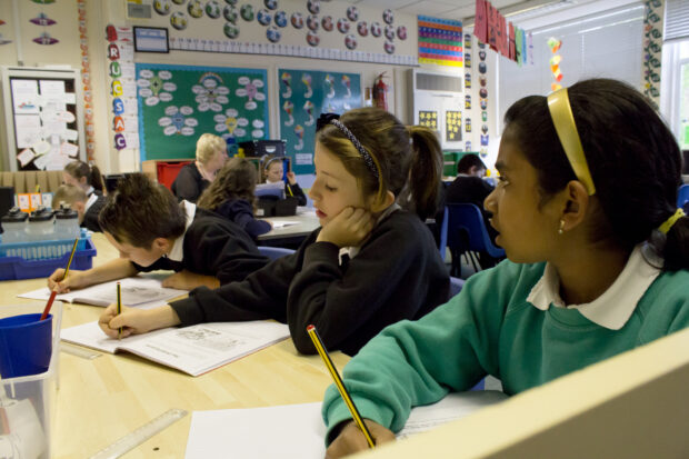 Classroom showing children writing in workbooks.