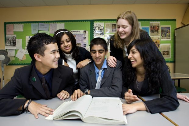 Children and teachers discussing a notebook.