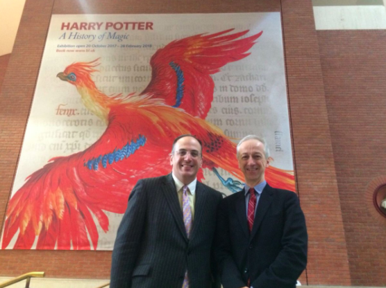Photo of 2 men standing in front of a Harry Potter: A History of Magic poster