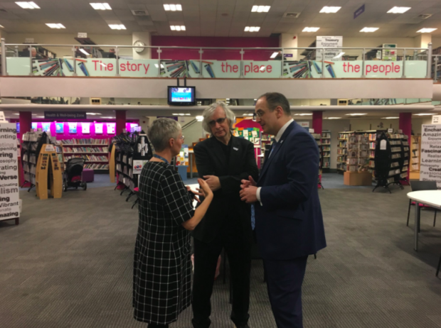 Photo of 3 people talking in a library.