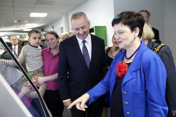 Cllr Ben Adams looks on as Baroness Neville-Rolfe explores the touch screens in the new Stafford library.