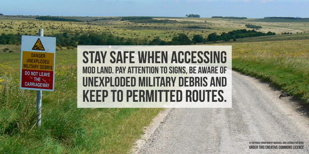 Pictured is a training area with a vehicle path and fields on either side. There is a warning sign that says danger unexploded military debris. The picture has text n the middle saying 'stay safe when accesing MOD land. Pay attention to signs, be aware pf unexploded military debris and keep to permitted routes.