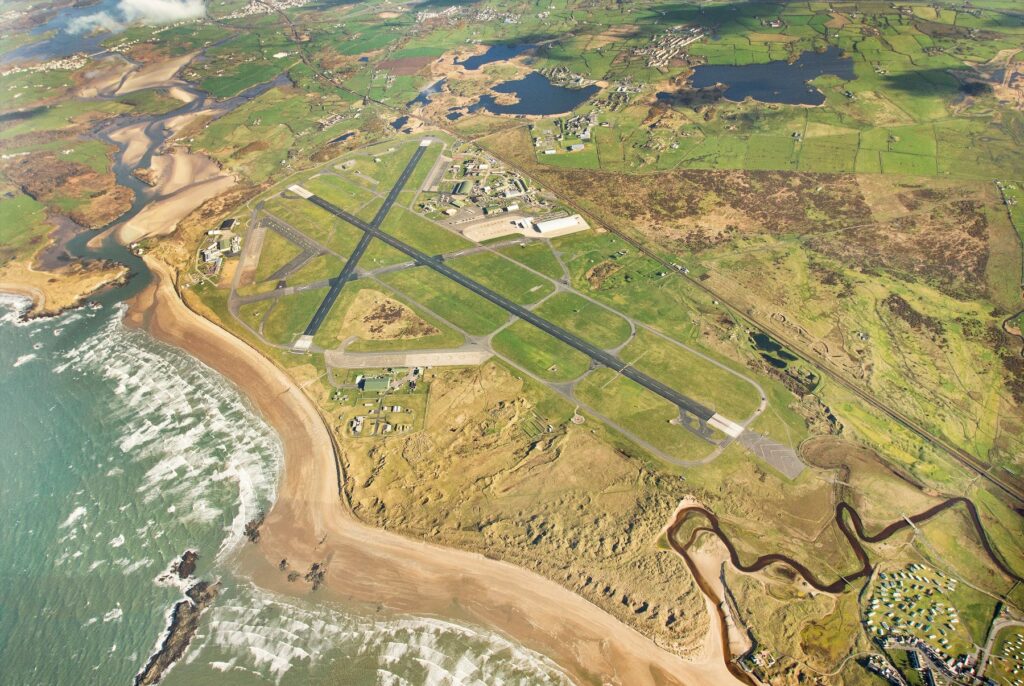 An aerial view of RAF Valley, with the beach and two runways in particular very visible.