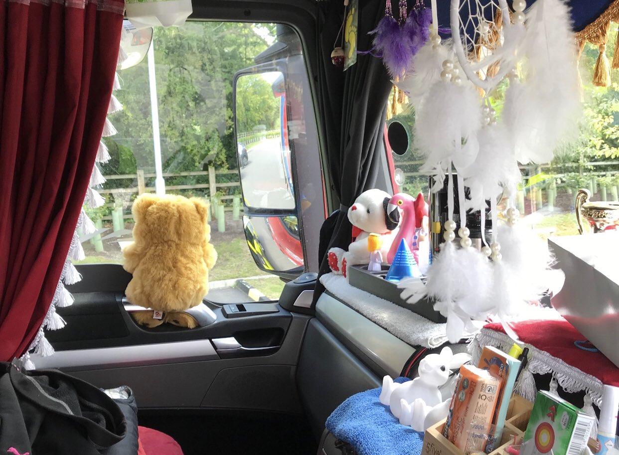 Cluttered lorry cab showing hanging toys, trinkets and fringed curtains
