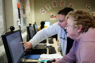 Photo of man teaching a woman to use computer