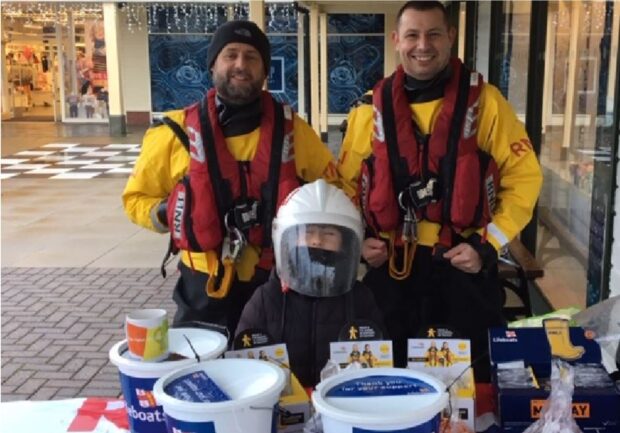 Dareen and Chris stood at a table with a bucket collection for the lifeboat fund