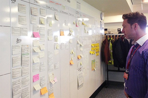 A man looking at sticky notes on a board.
