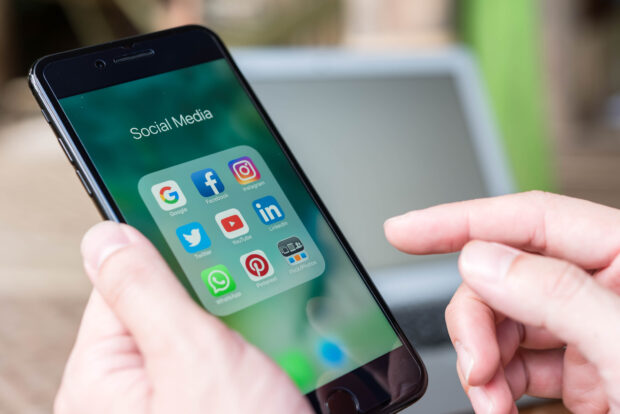 A mobile phone displaying a folder called 'Social Media' that contains various social media apps.