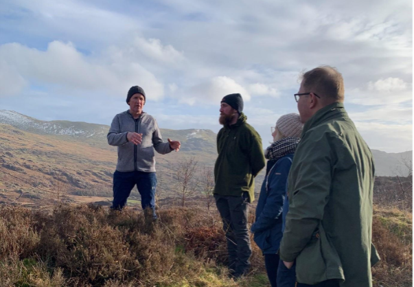 Caption: On a recent trip to Cumbria, Alan Laidlaw (right) met with Paddy Deady and Mark Hodgson (far left) who shared some of the initiatives which form part of their Landscape Recovery project in the Duddon Valley. The group stand on open ground under cloudy skies.