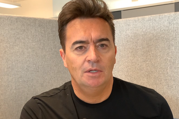 A man with dark hair wearing a black t shirt.