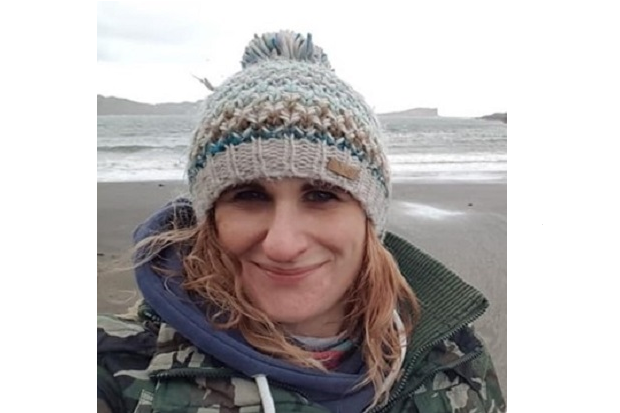 A lady with a bobble hat and the sea behind her.