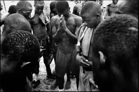 Members of local football team the 'Millennium Stars' pray before the start of a training session in Monrovia, Liberia. 1999.