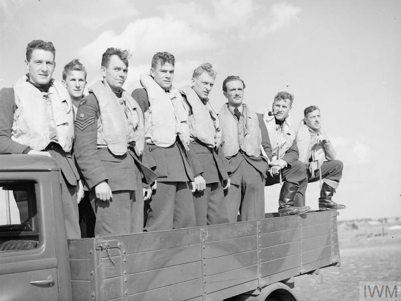 Eight pilots stood in the open back of a truck.