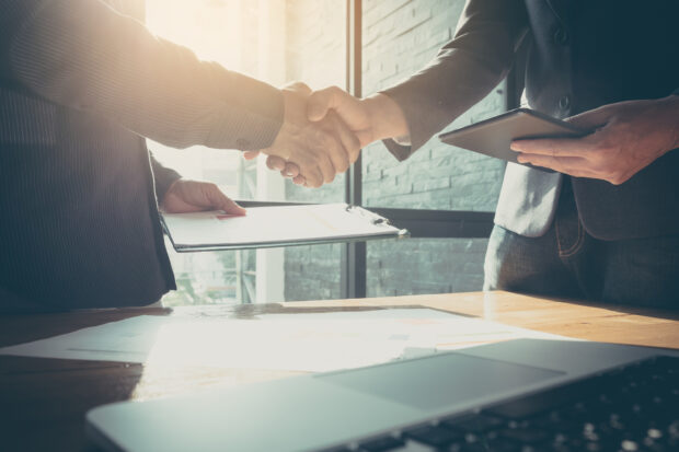 Business man and partner shaking hands in office