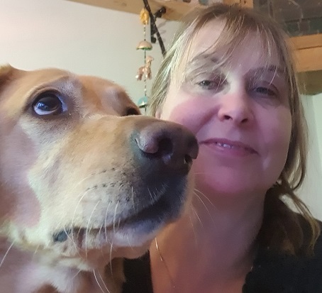 On the right, a close up of a dog's face, and on the left a lady with long hair, smiling at the dog.