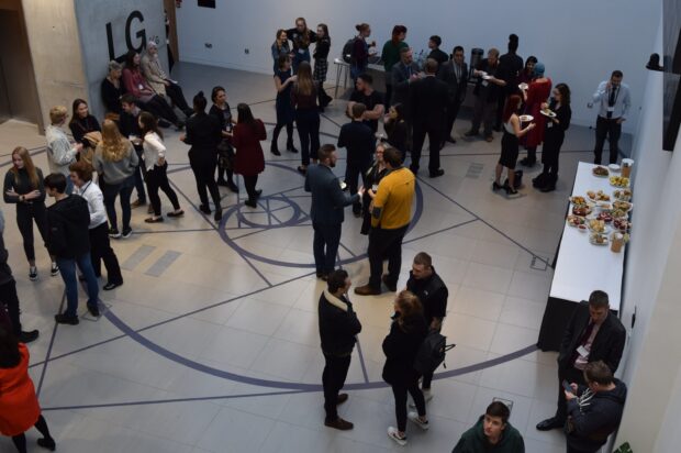 A group of people having a discussion in a hallway before the event