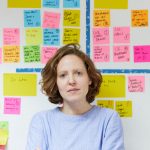 Headshot of Isabelle Andrews in front of an agile wall with postits on