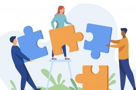 men and women holding giant jigsaw pieces to form a picture