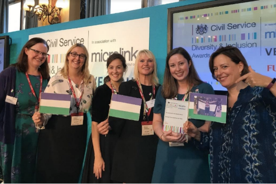Members of the Suffrage Centenary Volunteer Team at the Foreign and Commonwealth Office awards ceremony, with their award for winning the Championing Gender Equality category in the 2018 Civil Service Diversity and Inclusion Awards; and (right) award presenter Melanie Dawes, Civil Service Gender Champion