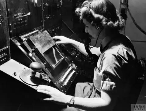 WAAF radar operator Denise Miley plotting aircraft on the CRT (cathode ray tube) of an RF7 Receiver in the Receiver Room at Bawdsey CH. 