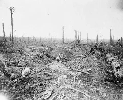 Soldiers digging a communication trench through Delville Wood. An officer observing from the ruins of Longueval Church.