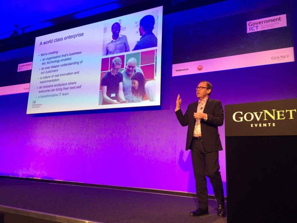 Pete Schofield standing on the stage at the Gov ICT conference delivering his talk