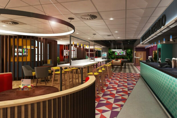 A futuristic looking dining and lounge area. There is a bar, tables and chairs, and a pool table and TV at the far end of the image. The colours across the walls and flooring are bright and varied.