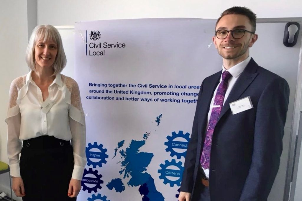 Two members of the project team standing by a CS Local banner