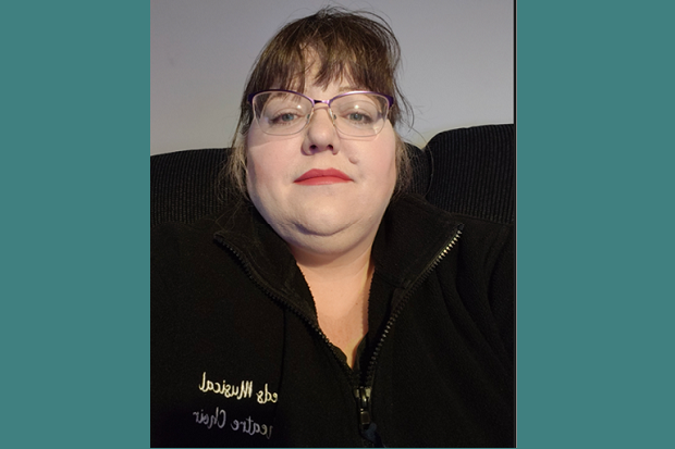 A lady, wearing glasses and a black zipped sweater.