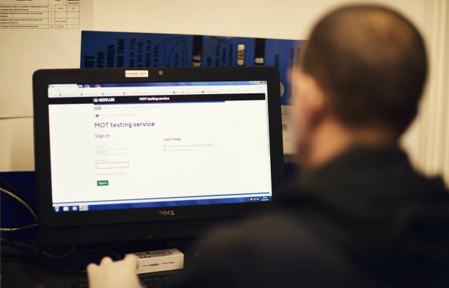 An over the shoulder shot of an MOT tester looking at the MOT testing service