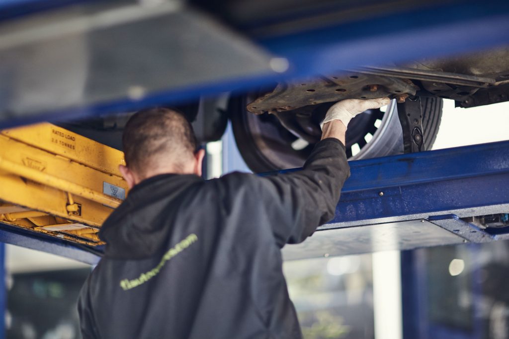 MOT tester inspecting under car
