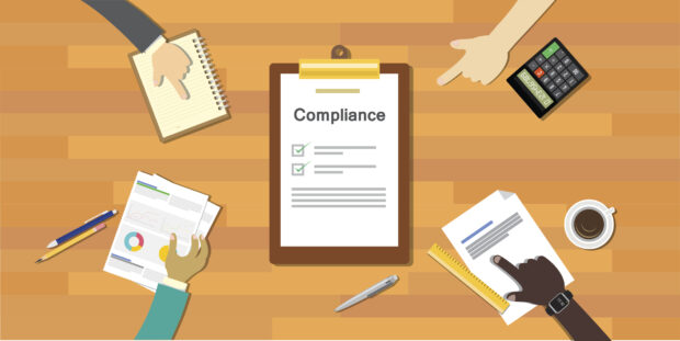 Flip chart with the word compliance on, in the middle of a table