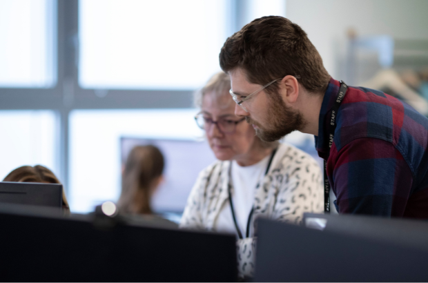 Two caseworkers examine the details of a case on screen, both looking intently.