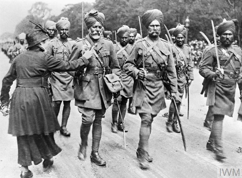 A woman pins flowers on to the tunic of a soldier at a march-past of Indian troops.