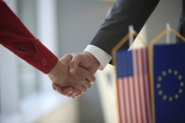 Handshake in front of Usa and Eu flags