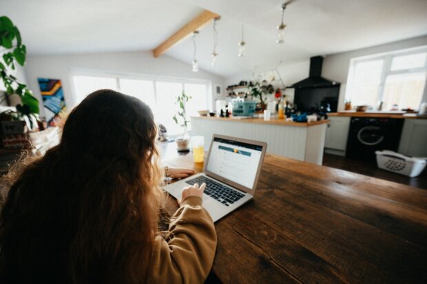 A woman typing on a laptop in her kitchen.