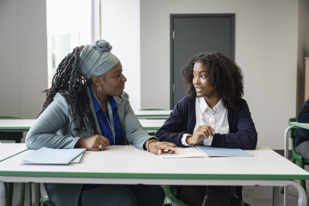 An adult speaking to a student about her work