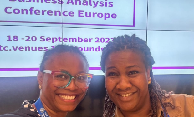 2 women smiling and standing in front of a screen