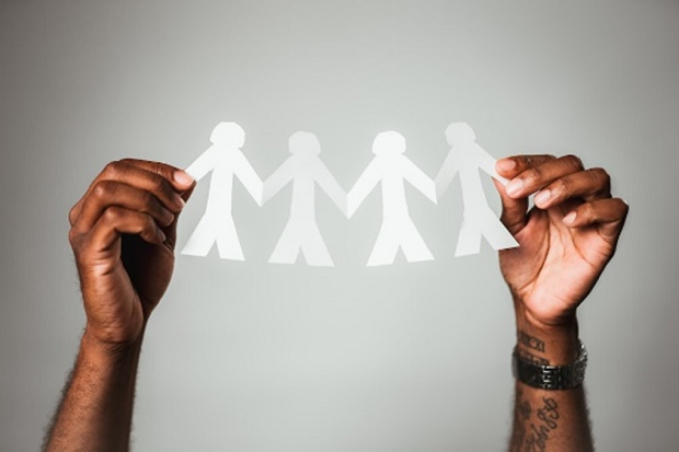 A pair of hands holding up a chain of paper dolls