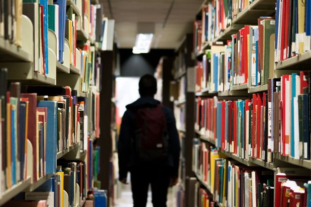 silhouette of a young person in a library surrounded by books