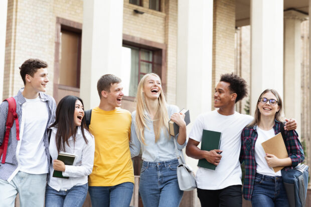 Group of students walking in a row, arms linked, looking happy.excited