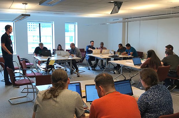 Groups of staff sat around laptops working on the AWS gameday project