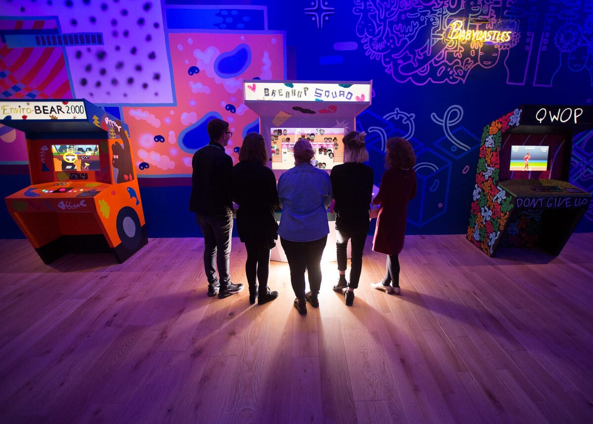 A group of people standing around an arcade machine at V&A Dundee