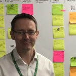 Ken Robers stood next to a whiteboard with post-its on