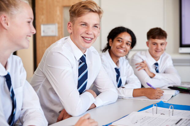 Secondary school pupils in uniform smiling to camera